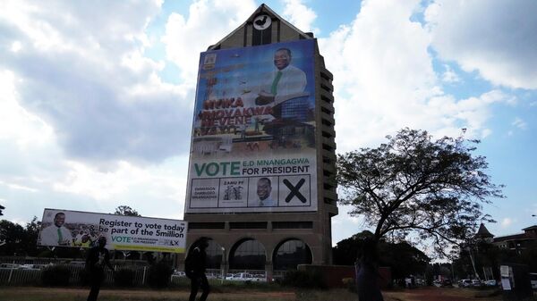 People walk past an election poster of Zimbabwean President Emmerson Mnangagwa at the party headquarters in Harare on June, 8, 2023.  - Sputnik Africa