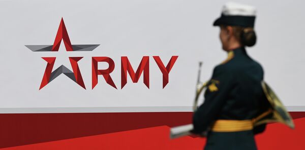 A member of the Russian military music orchestra walks past a banner with the logo of the International Military-Technical Forum ARMY-2023 at the Patriot Exhibition and Convention Center on August 15, 2023. - Sputnik Africa