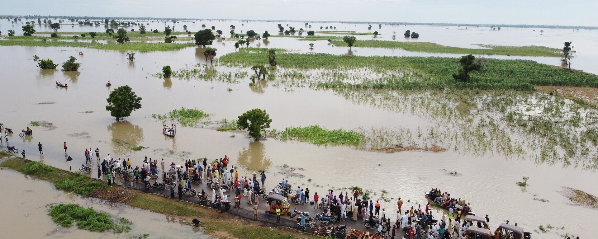 People walk through floodwaters near flooded farmlands after heavy rainfall in Hadeja, Nigeria, Sept 19, 2022. - Sputnik Africa, 1920, 18.08.2023