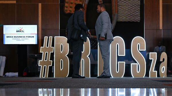 Men stand next to an installation with the logo of BRICS during the 15th BRICS Summit in Johannesburg, South Africa, on Tuesday, August 22, 2023. - Sputnik Africa