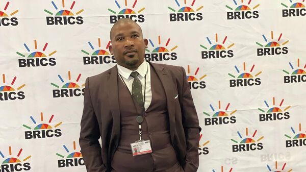 Trevor Tambo, a South African businessman and member of the BRICS Business Council's Finance Working Group, poses for a photo near BRICS banner at the 15th BRICS Summit in Johannesburg, South Africa, on August 22, 2023. - Sputnik Africa