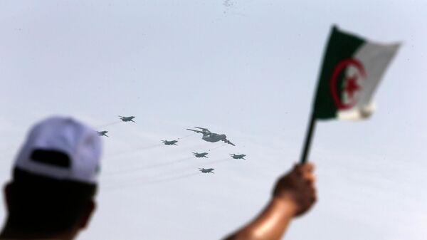 A man waves an Algerian flag as war planes fly during a military parade to mark the 60th anniversary of Algeria's independence, Tuesday, July 5, 2022 in Algiers.  - Sputnik Africa