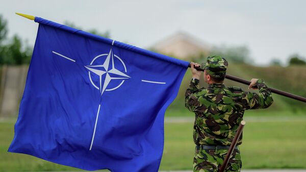 A Romanian serviceman furls the NATO flag. File photo - Sputnik Africa