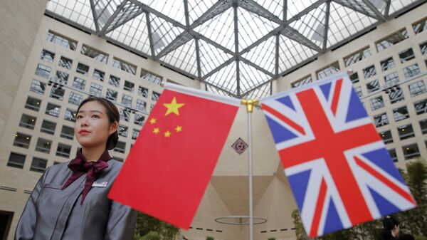 A member of staff stands behind flags as officials arrive for the UK-China High Level Financial Services Roundtable at the Bank of China head office building in Beijing on July 22, 2016 - Sputnik Africa