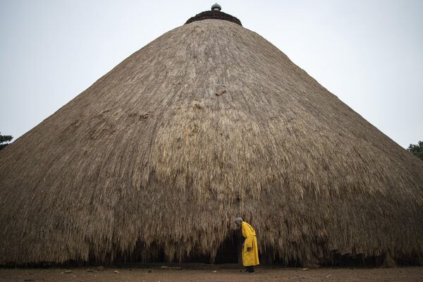 A traditional guard stands in front of one of the buildings belonging to the Kasubi Royal Tombs in Kampala, Uganda. - Sputnik Africa
