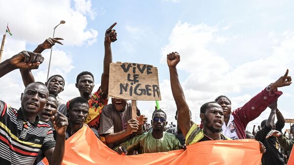 Supporters of the Niger's National Council for the Safeguard of the Homeland (CNSP) wave a placard as they demonstrate ouside the Niger and French airbases in Niamey on August 27, 2023. - Sputnik Africa