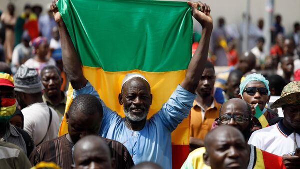 Un partisan du Président de la Transition brandit le drapeau du Mali lors d'un rassemblement. - Sputnik Afrique