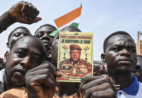 A man holds a placard with the image of Niger&#x27;s new military ruler General Abdourahamane Tiani on as supporters of Niger&#x27;s National Council of Safeguard of the Homeland (CNSP) protest outside the Niger and French airbase in Niamey on September 2, 2023 to demand the departure of the French army from Niger. - Sputnik Africa