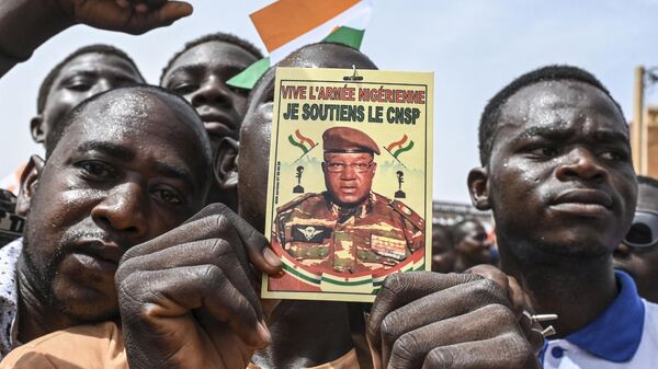A man holds a placard with the image of Niger's new military ruler General Abdourahamane Tiani on as supporters of Niger's National Council of Safeguard of the Homeland (CNSP) protest outside the Niger and French airbase in Niamey on September 2, 2023 to demand the departure of the French army from Niger. - Sputnik Africa