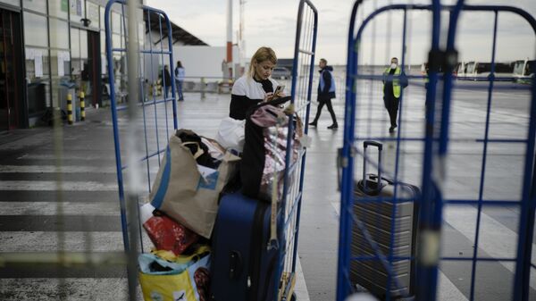 A woman from Ukraine checks her mobile as she arrives with her belongings at the temporary refugee shelter.  - Sputnik Africa