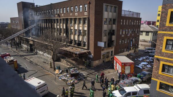 Medics stand by the covered bodies of victims of a deadly blaze in downtown Johannesburg, South Africa - Sputnik Africa