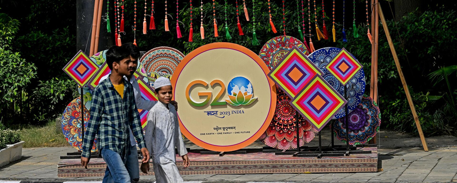 Pedestrians walk next to a G20 India summit logo ahead of its commencement in New Delhi on September 3, 2023.  - Sputnik Africa, 1920, 04.09.2023