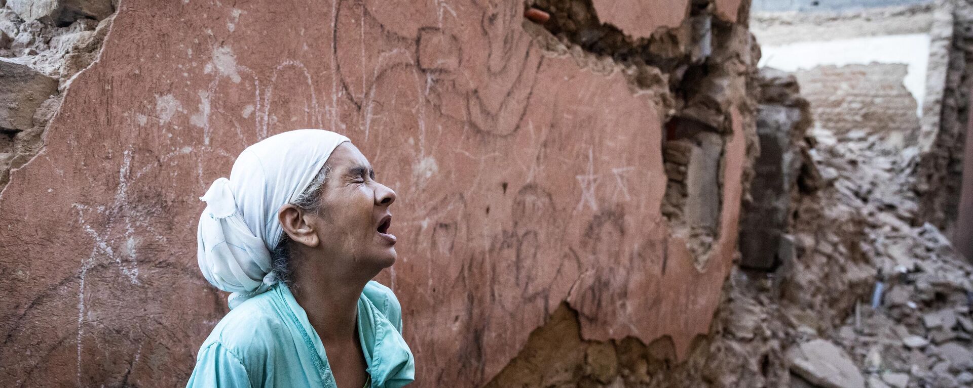 A woman reacts standing infront of her earthquake-damaged house in the old city in Marrakesh on September 9, 2023. A powerful earthquake that shook Morocco late September 8 killed more than 600 people, interior ministry figures showed, sending terrified residents fleeing their homes in the middle of the night. - Sputnik Africa, 1920, 09.09.2023