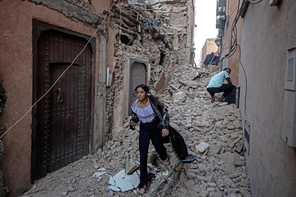 A woman evacuates with her belongings through the rubble in the earthquake-damaged old city of Marrakesh on September 9, 2023. A powerful earthquake that shook Morocco late September 8 killed more than 600 people, interior ministry figures showed, sending terrified residents fleeing their homes in the middle of the night.  - Sputnik Africa