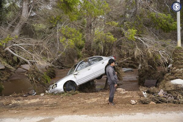 A car sits partly suspended in trees after being carried by floodwaters in Derna. - Sputnik Africa