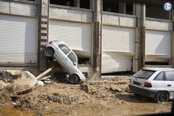 A car sits suspended against a shop front after being carried by floodwaters in Derna. - Sputnik Africa