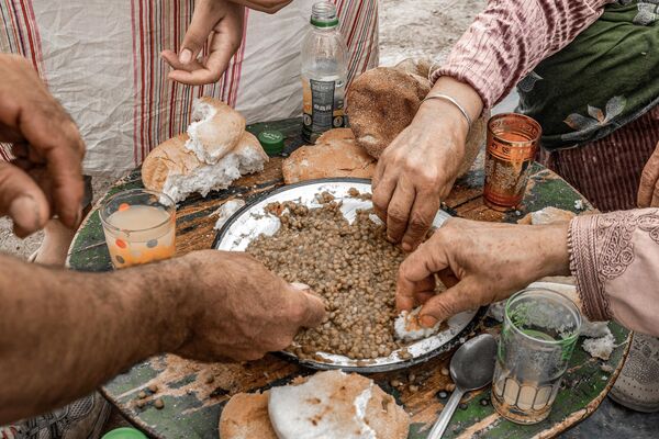 Displaced earthquake survivors share a meal of lentils for lunch in their tent in a village near Amizmiz on September 13. - Sputnik Africa