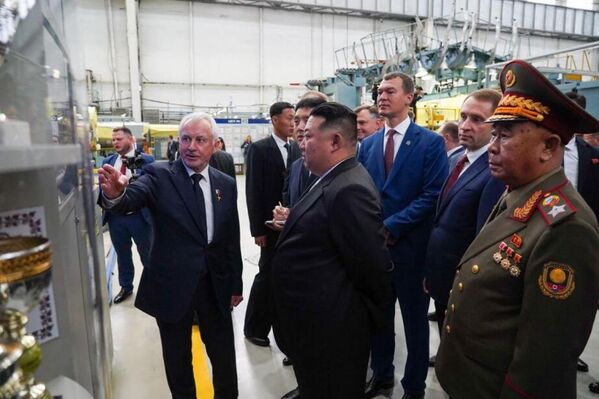 The DPRK leader and Khabarovsk governor listen to an employee guiding them who explains the characteristics of aircraft produced at the  plant. - Sputnik Africa