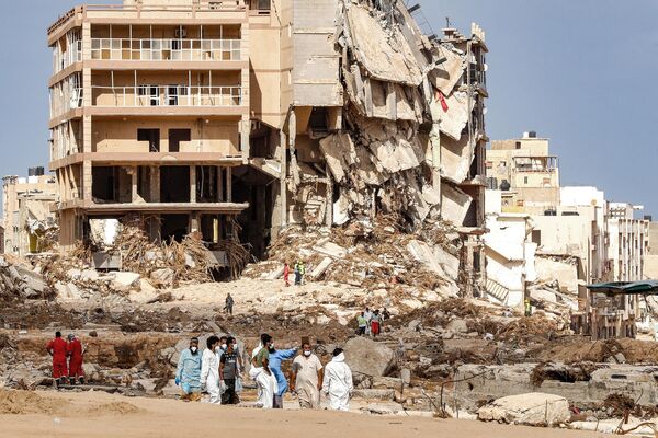 Rescue teams walk in a destroyed area in Derna on September 18, 2023, following deadly flash floods. - Sputnik Africa
