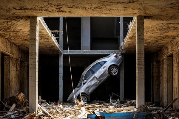 A tilted car sits above debris in Derna on September 18, 2023. - Sputnik Africa
