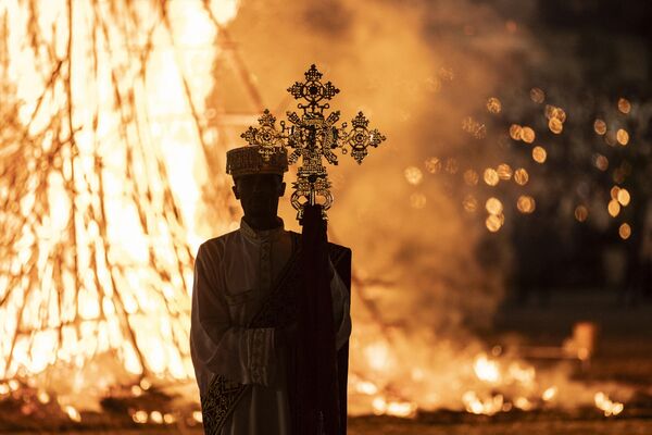 A high priest holds a cross while standing in front of a bonfire during the celebrations of the Ethiopian Orthodox holiday of Meskel in Addis Ababa on September 27, 2023. - Sputnik Africa