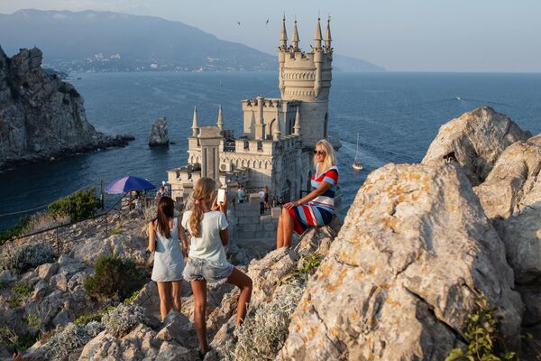 Tourists take pictures near the Swallow&#x27;s Nest castle on a coastal cliff in the village of Gaspra in Crimea. - Sputnik Africa