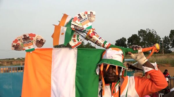 Un manifestant portant des drapeaux du Niger à Niamey - Sputnik Afrique
