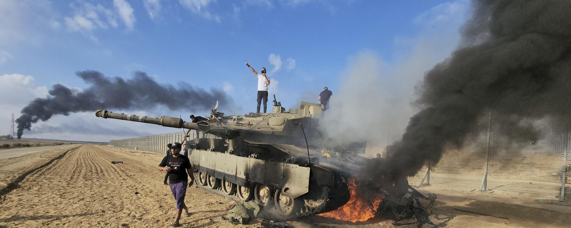 Palestinians celebrate by a destroyed Israeli tank at the Gaza Strip fence east of Khan Younis southern Saturday, Oct. 7, 2023. - Sputnik Africa, 1920, 07.10.2023