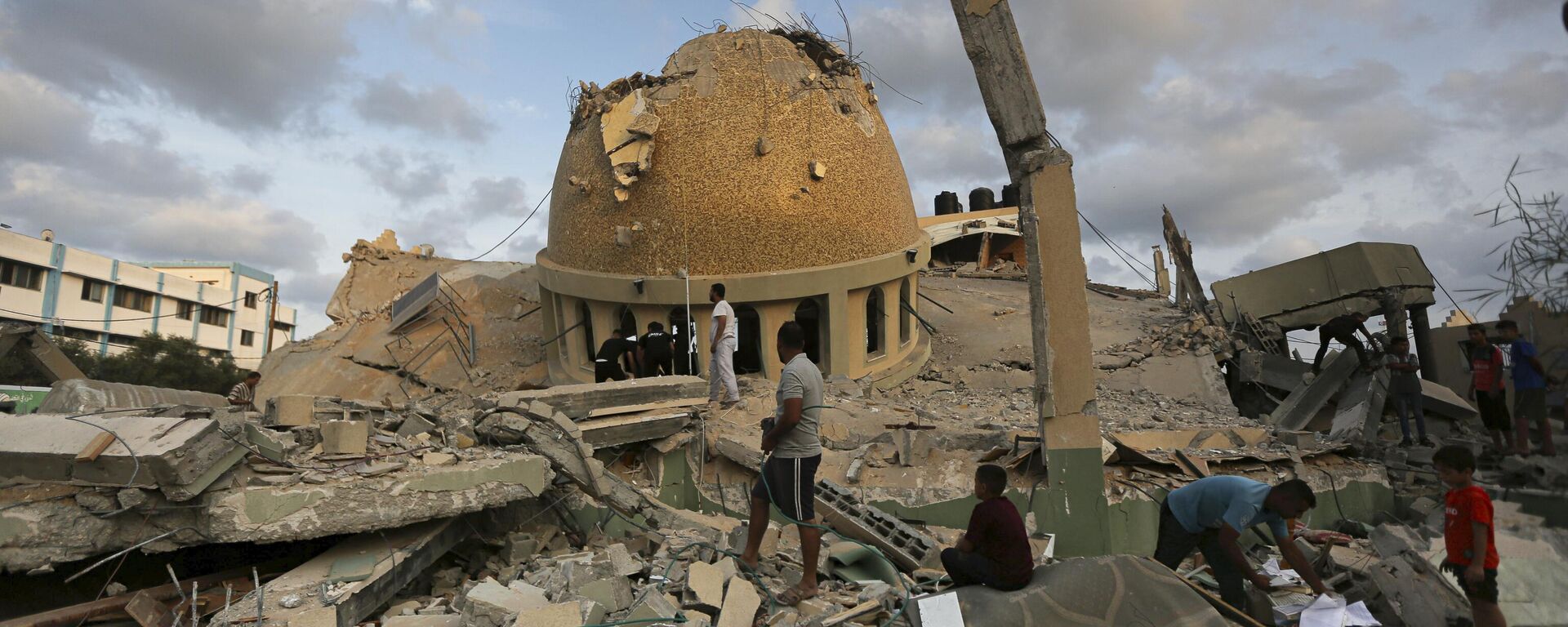 People stand outside a mosque destroyed in an Israeli air strike in Khan Younis, Gaza Strip, Sunday, Oct.8, 2023.  - Sputnik Africa, 1920, 08.10.2023