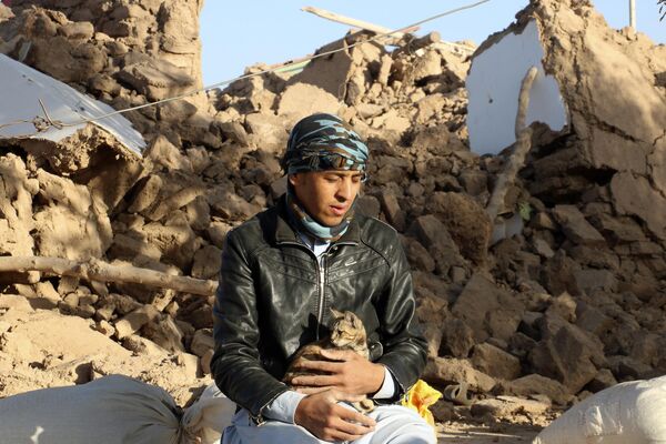 An Afghan boy hold his cat, as he sits in a courtyard of his destroyed home after an earthquake in Zendeh Jan district. - Sputnik Africa