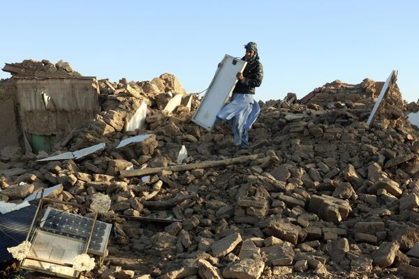 An Afghan man removes debris after an earthquake in western Afghanistan. - Sputnik Africa