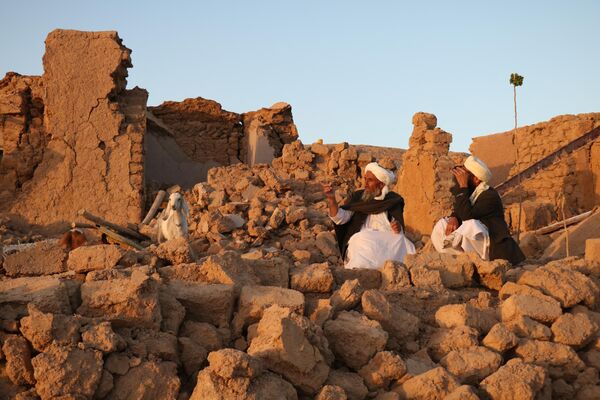 Afghan residents sit at a damaged house after earthquake in Sarbuland village of Zendeh Jan district. - Sputnik Africa