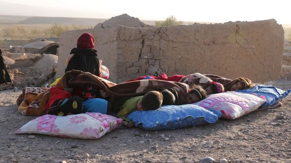 Afghan children rest under a blanket beside damaged houses after earthquake in Sarbuland village of the district. - Sputnik Africa