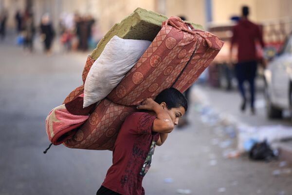 A boy carries a mattres as Palestinians with their belongings flee to safer areas in Gaza City after Israeli air strikes, on October 13, 2023. Israel has called for the immediate relocation of 1.1 million people in Gaza amid its massive bombardment in retaliation for Hamas&#x27;s attacks, with the United Nations warning of &quot;devastating&quot; consequences.  - Sputnik Africa