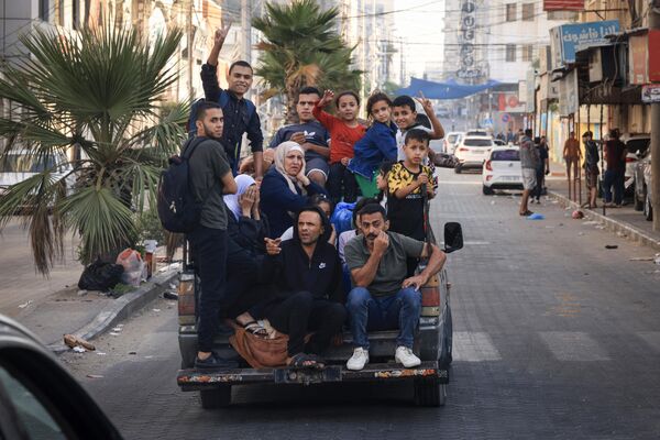 Palestinians flash the V for victory sign as they flee to safer areas in Gaza City after Israeli air strikes, on October 13, 2023. - Sputnik Africa