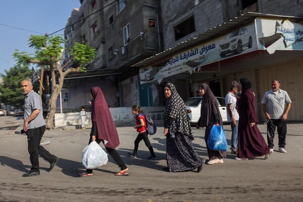 Palestinians carrying their belongings flee to safer areas in Gaza City after Israeli air strikes, on October 13, 2023.  - Sputnik Africa