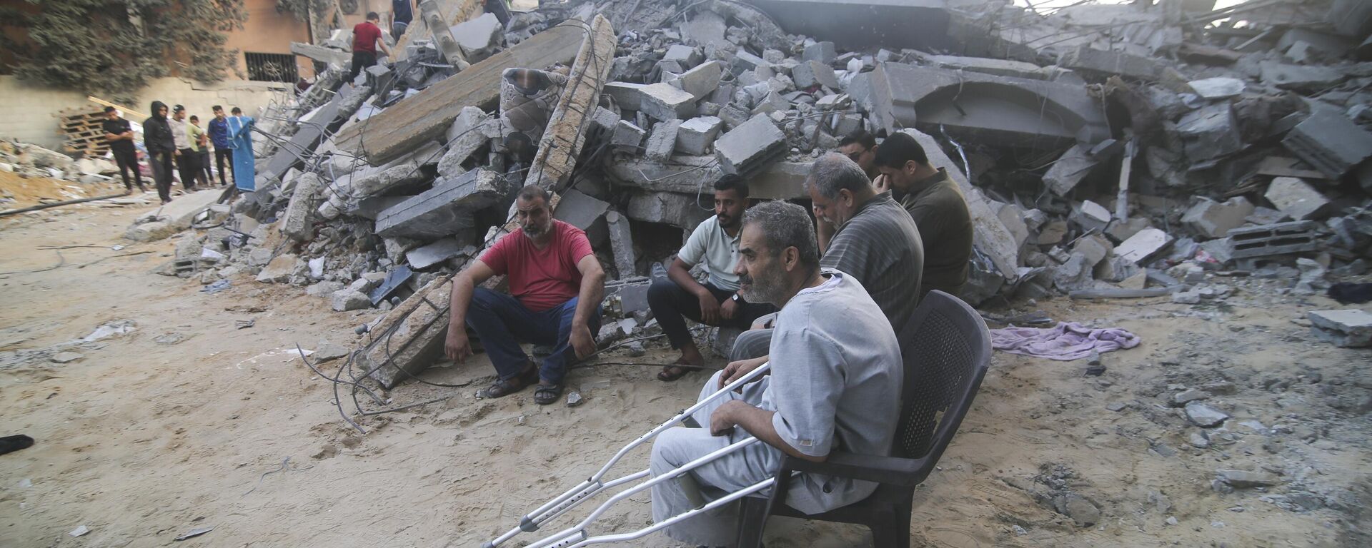 Palestinians sit by the building destroyed in an Israeli airstrike in Rafah, Gaza Strip, Saturday, Oct. 14, 2023.  - Sputnik Africa, 1920, 16.10.2023