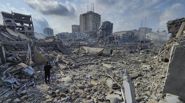Палестинцы идут через обломки зданий, разрушенных в результате израильских авиаударов в городе Газа, 10 октября 2023 года - Sputnik Africa