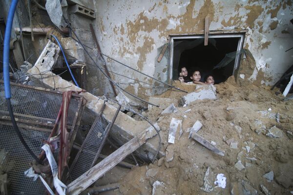 Palestinian children look at the building of the Zanon family, destroyed in Israeli airstrikes in Rafah, the Gaza Strip, Saturday, Oct. 14, 2023.  - Sputnik Africa