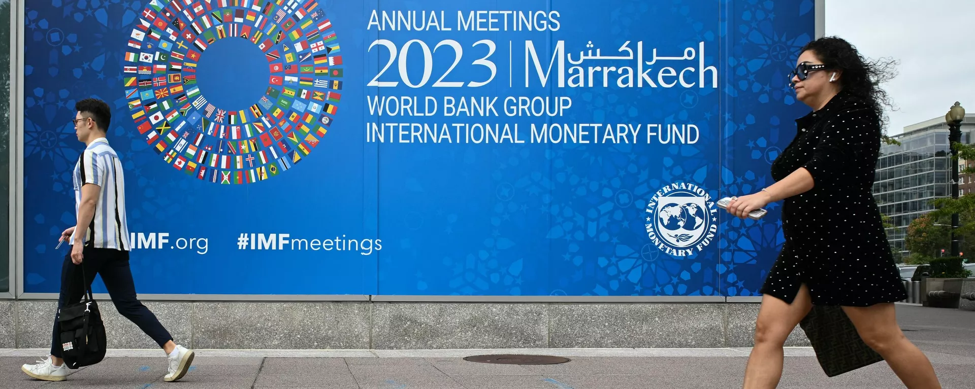 Pedestrians walk past a billboard announcing the World Bank Group and International Monetary Fund annual meetings, on the side of the International Monetary Fund headquarters in Washington DC on October 5, 2023.  - Sputnik Africa, 1920, 16.10.2023