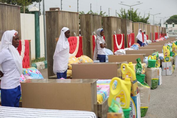 Household items given to couples are seen beside brides at the venue of a wedding reception at the Kano state governor&#x27;s office after taking part in the mass wedding. - Sputnik Africa