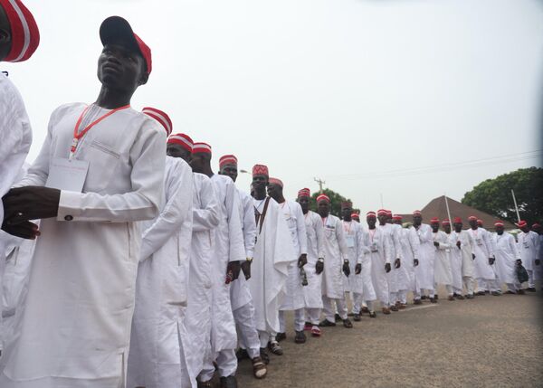 Grooms dressed in white robes and red caps walk on the street of Kano to attend a wedding reception at the Kano state governor&#x27;s office after taking part in the ceremony. - Sputnik Africa