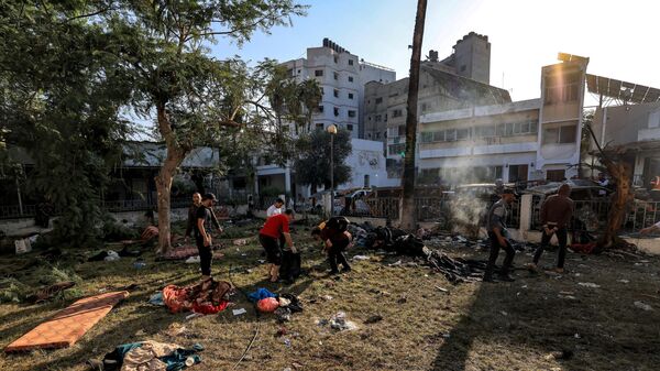 People search through debris outside the site of the Ahli Arab hospital in central Gaza on October 18, 2023 in the aftermath of an overnight blast there.  - Sputnik Africa