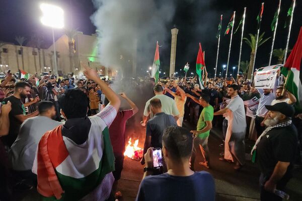 People burn a US flag during a protest in Libya&#x27;s capital Tripoli late on October 17, 2023, in support of Palestinians following a strike on the Ahli Arab hospital in central Gaza which killed hundreds. Israel and Palestinians traded blame for the incident, which an &quot;outraged and deeply saddened&quot; US President Joe Biden denounced while en route to the Middle East.  - Sputnik Africa