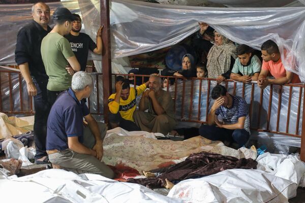 [Graphic content] Relatives mourn over the bodies of Palestinians killed in a strike on the Ahli Arab hospital in central Gaza after they were transported to Al-Shifa hospital, on October 17, 2023. Israel and Palestinians traded blame for the incident, which an &quot;outraged and deeply saddened&quot; US President Joe Biden denounced while en route to the Middle East.  - Sputnik Africa