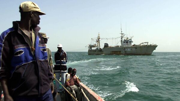 The captain of the M Baye Daba looks on as his boat passes the fishing trawler Marsor Primero from South Korea near the town of Joal, about 93 miles from Dakar, Jan. 15, 2003. - Sputnik Africa