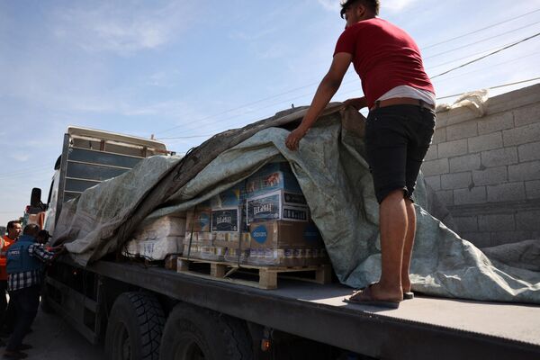 A worker organizes food aid after a convoy of trucks entered the Palestinian side of the Rafah border crossing with Egypt. - Sputnik Africa