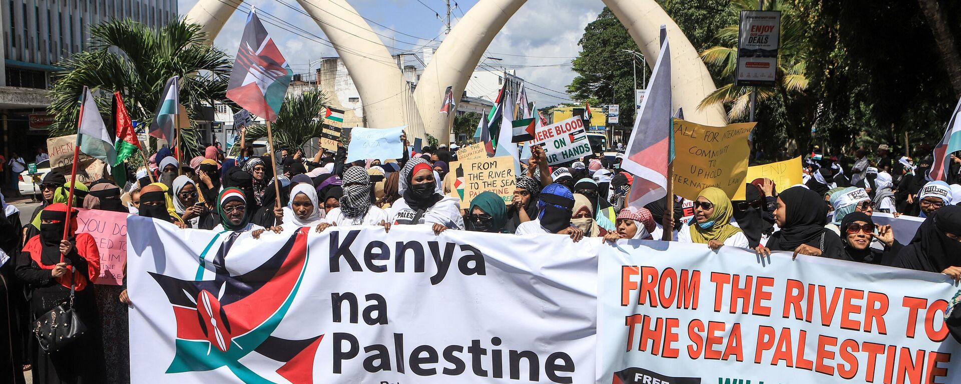 Members of the muslim community in Kenya hold banners as they wave Palestinian flags and chant slogans during a demonstration in solidarity with Palestine in Mombasa on October 21, 2023.  - Sputnik Africa, 1920, 22.10.2023