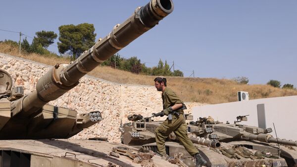 An Israeli soldier walks on a Merkava tank at a position in an undisclosed location on the border with Lebanon on October 22, 2023.  - Sputnik Africa