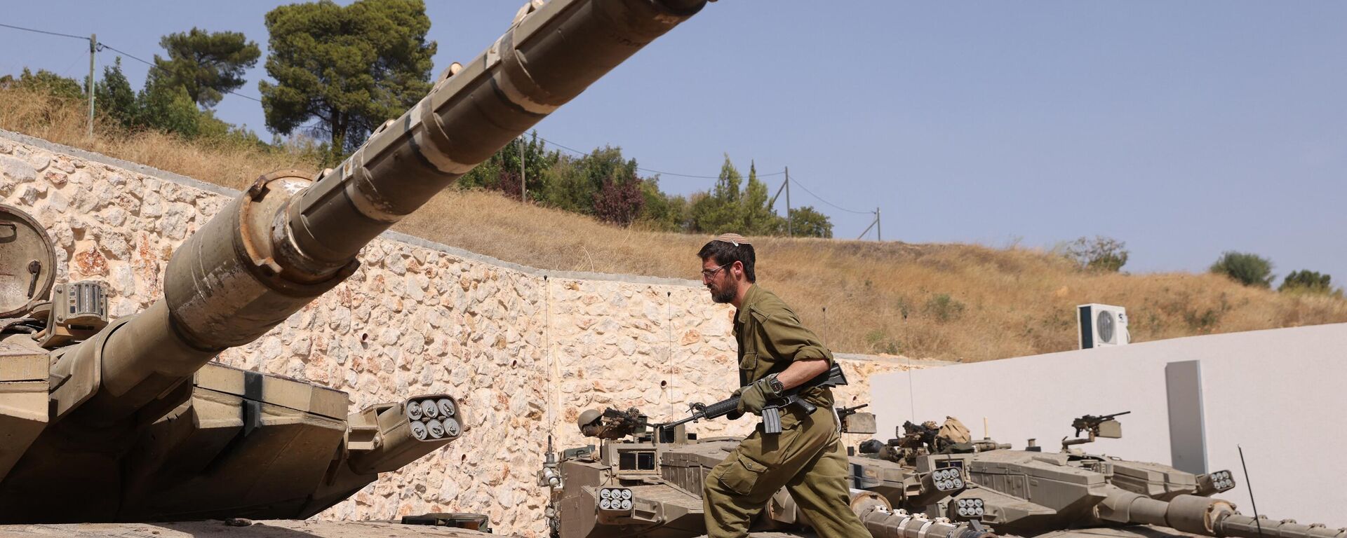 An Israeli soldier walks on a Merkava tank at a position in an undisclosed location on the border with Lebanon on October 22, 2023.  - Sputnik Africa, 1920, 22.10.2023